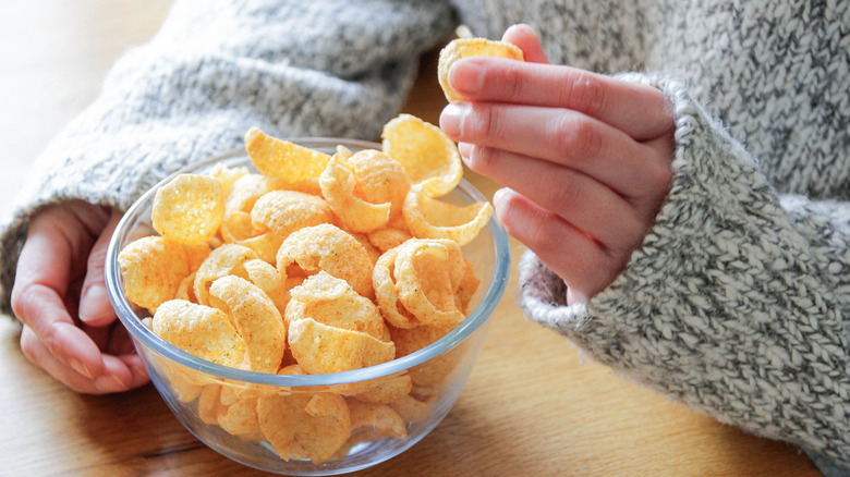 A person snacking on a bowl of chips