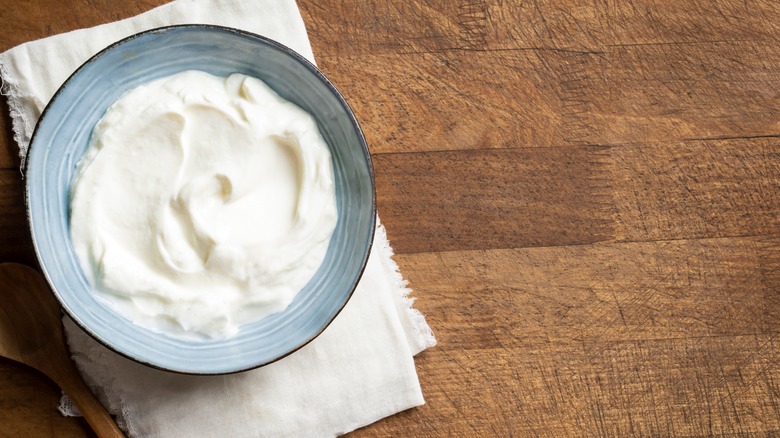 A blue bowl filled with fresh sour cream on a brown table