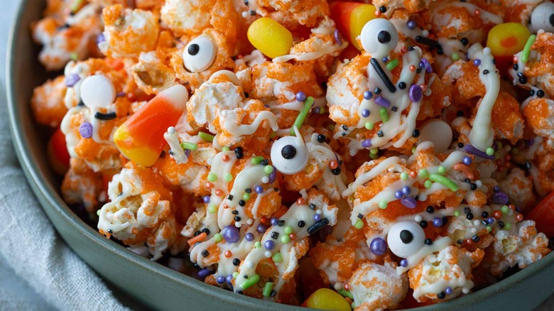 orange coated popcorn with googly eyes and candy corn