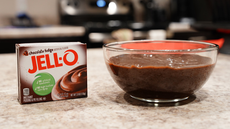 A box of Jell-O pudding mix next to a bowl of chocolate pudding