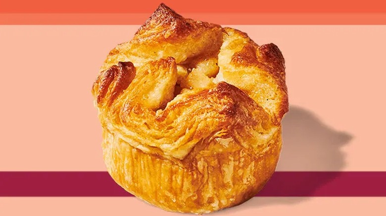 a promotional picture of the baked apple croissant on a peach, orange and maroon background