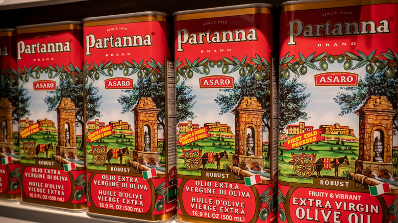 Cans of extra virgin olive oil sit on a shelf