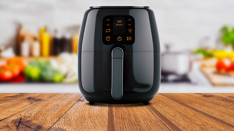 A black air fryer with orange buttons on a countertop