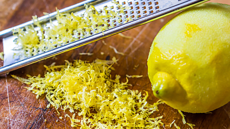 A grater, pile of lemon zest and a zested lemon