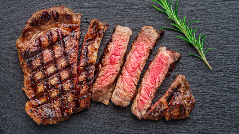 steak with slices on black board rosemary