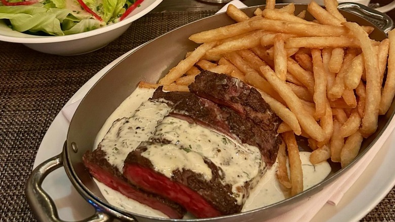 Steak in dish with fries and sauce