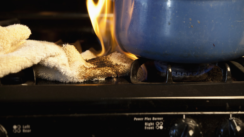 A towel catches on fire on a gas stove.