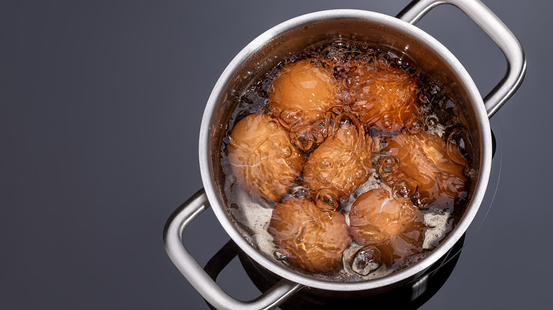 Seven eggs sit in a pot of boiling water.