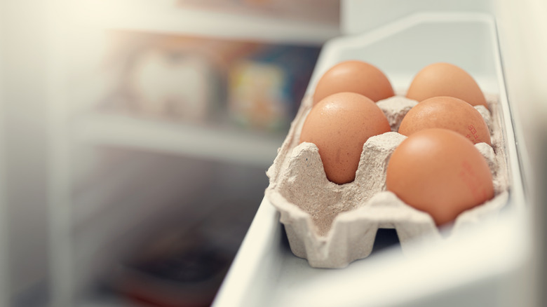 Five eggs are shown in an open refrigerator door.