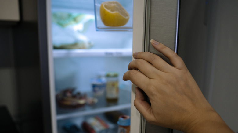 a hand opening a fridge door