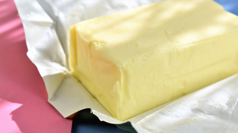 unwrapped butter on pink and blue background