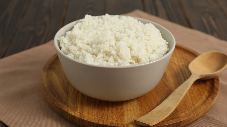 bowl of white rice next to wooden spoon