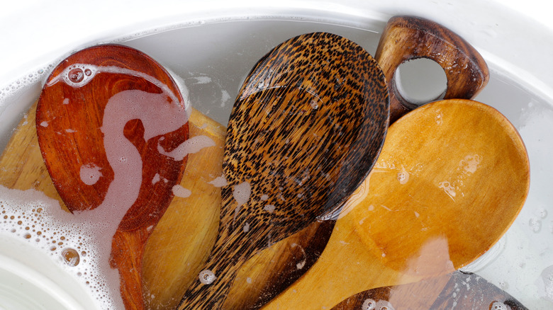 Wooden spoons being soaked in water with bubbles