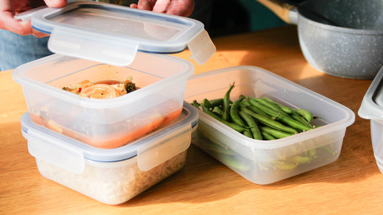 A person putting the lid on a plastic container of leftover food