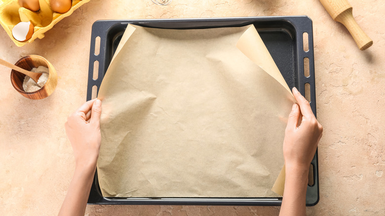 putting parchment paper onto baking pan