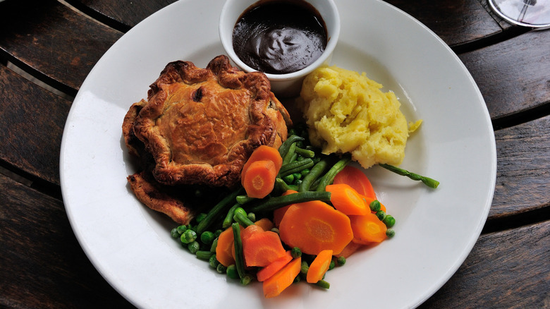 Suet pie with vegetables, gravy, and mashed potatoes