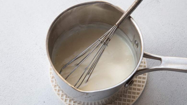 whisking white sauce in saucepan