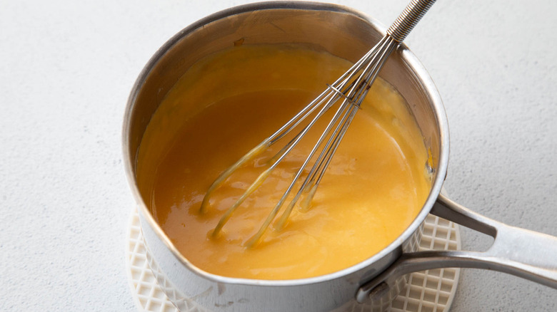 whisking cheese sauce in saucepan