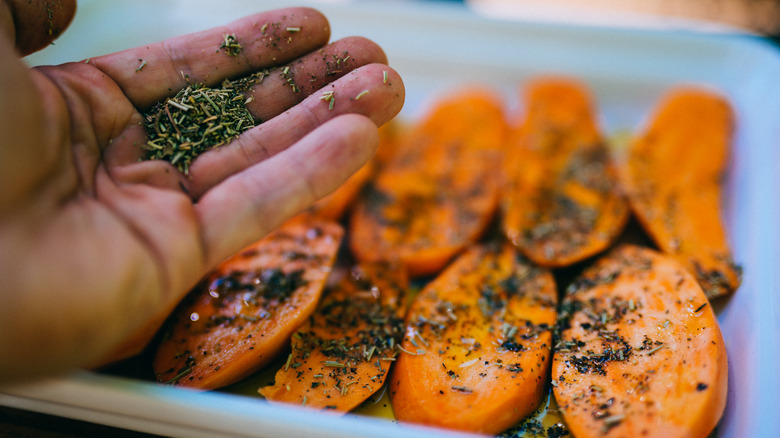 Someone seasoning sweet potato slices