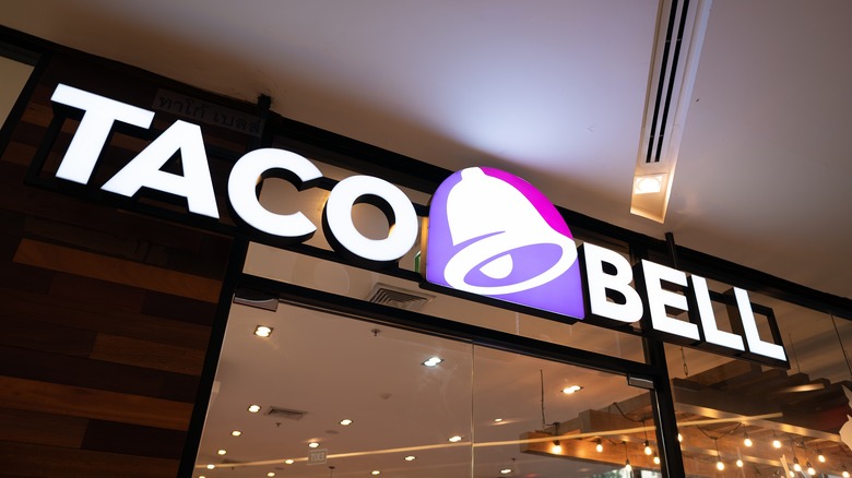 A Taco Bell sign above an interior window inside of a building.