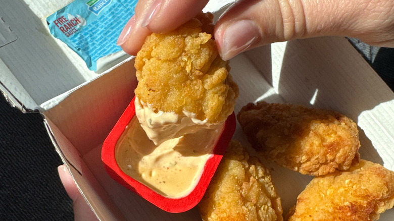 A Taco Bell Crispy Chicken Nuggets being dipped in Hidden Valley Fire Ranch Sauce