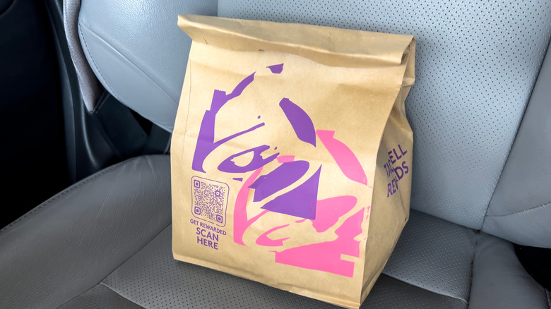 A bag of Taco Bell food sits on a car seat