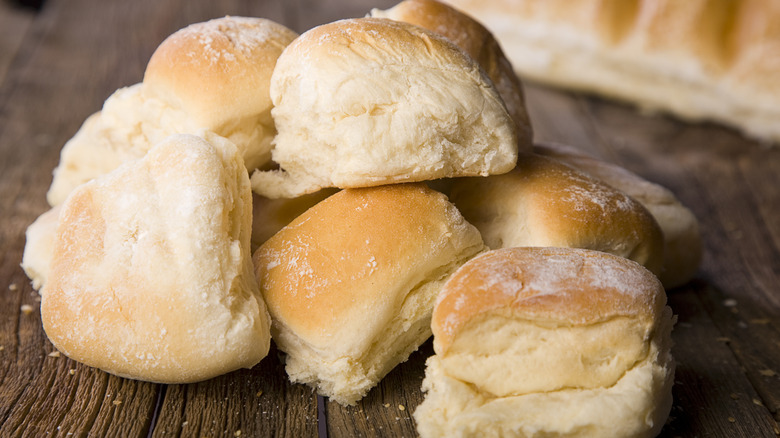 Pile of bread rolls stacked atop a wooden surface.