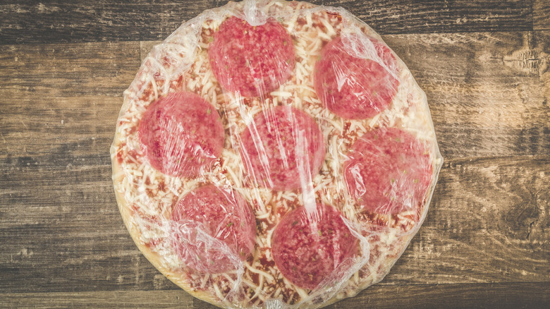 Frozen pizza in plastic wrap