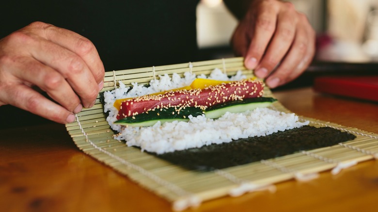 A chef rolling up a maki roll