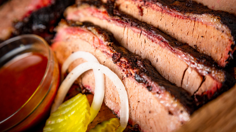 Slices of brisket, onion, pickle, and sauce are shown together