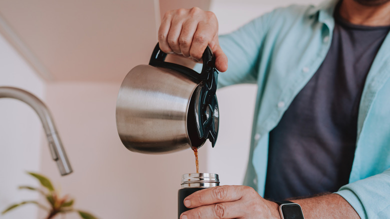 Person pouring coffee from thermal carafe