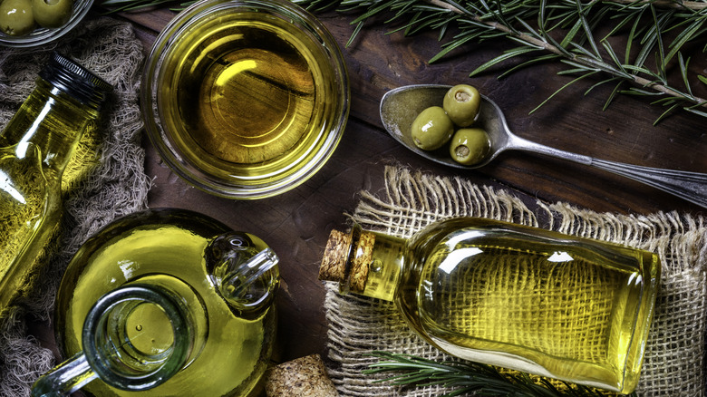 Bottles and jugs of olive oil with olives and herbs