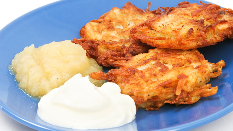 latkes on a blue plate with both sour cream and applesauce