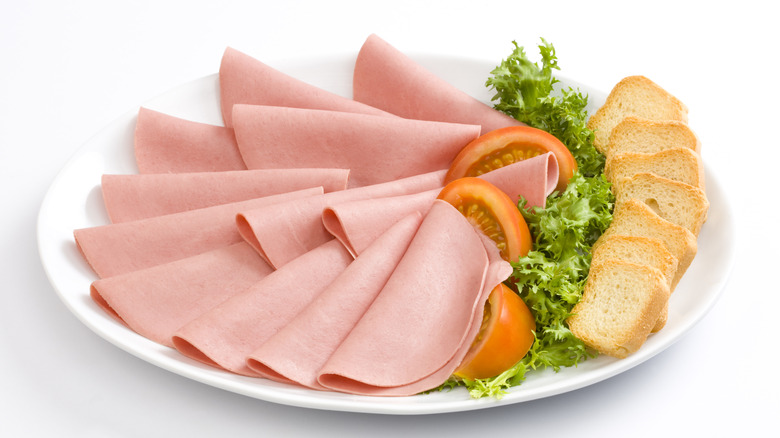 A platter of bologna with lettuce, tomato, and crispbread