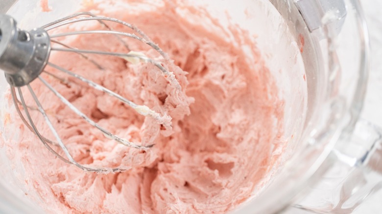 A whisk whipping a bowl of strawberry butter