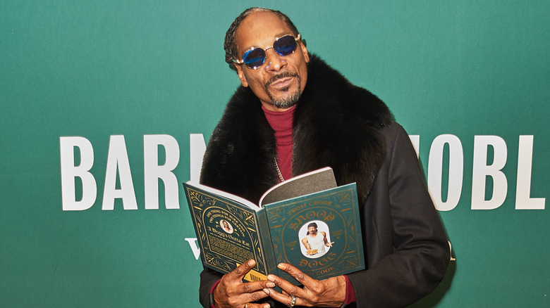 Snoop Dogg posing with his cookbook called From Crook to Cook