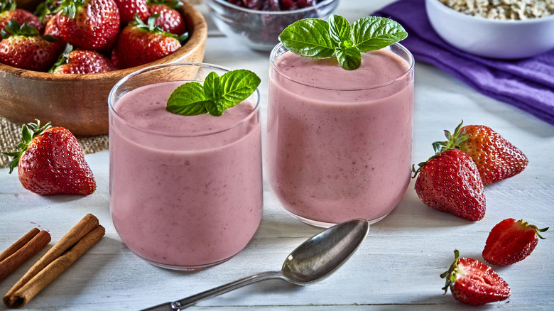 Two strawberry smoothies in glass cups sitting on a table