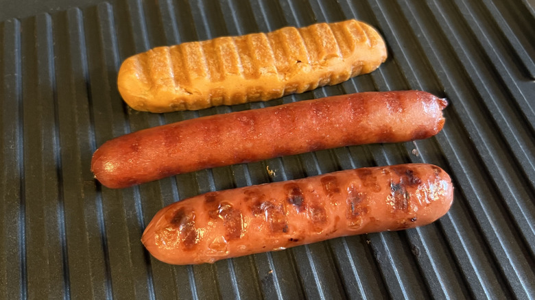 Three grilled hot dogs are in a line.