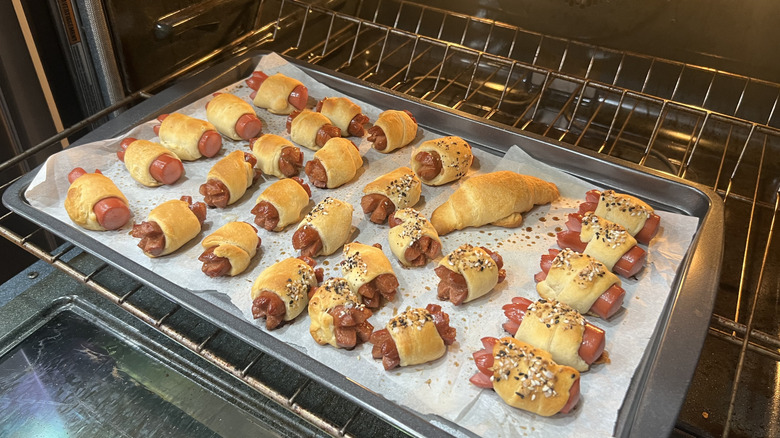 A tray of pigs in a blanket sits in the oven.