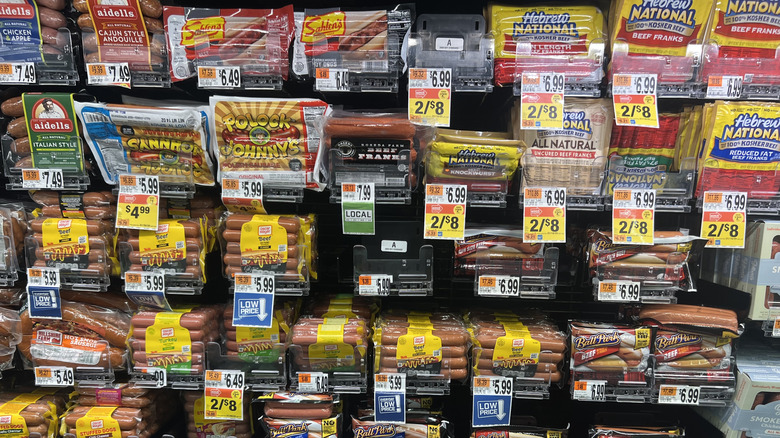 A grocery store shelf is filled with packaged hot dogs.