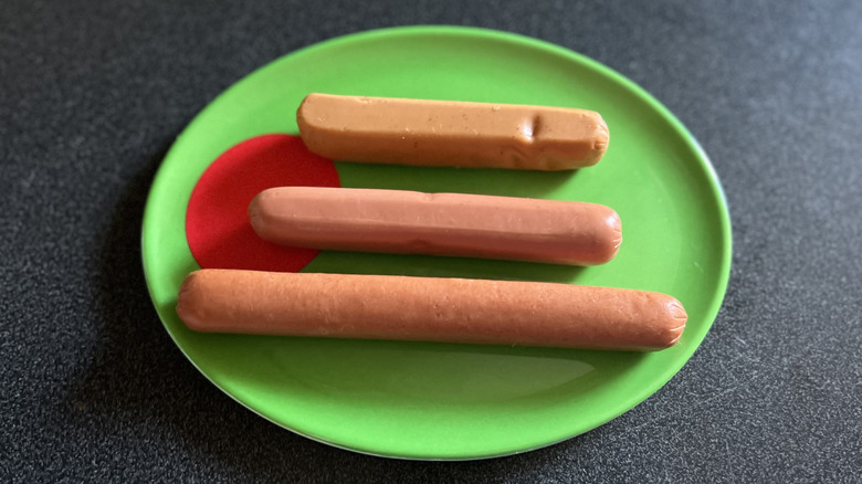 Three plain hot dogs are sitting on a green plate.