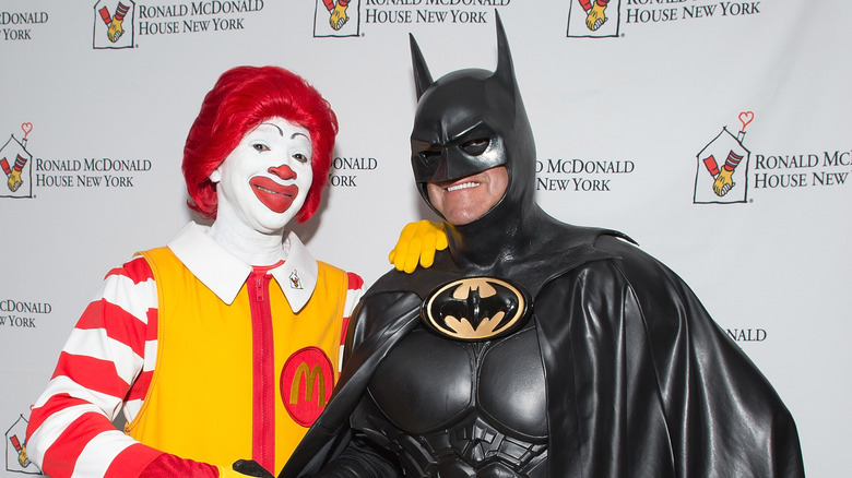 Ronald McDonald and Batman actors posing with each other in front of a Ronald McDonald House of New York backdrop