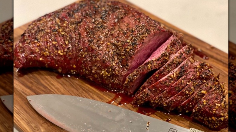 Grilled tri-tip steak on a cutting board with a knife