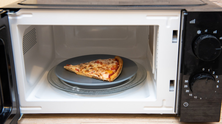 Pizza slice in black microwave