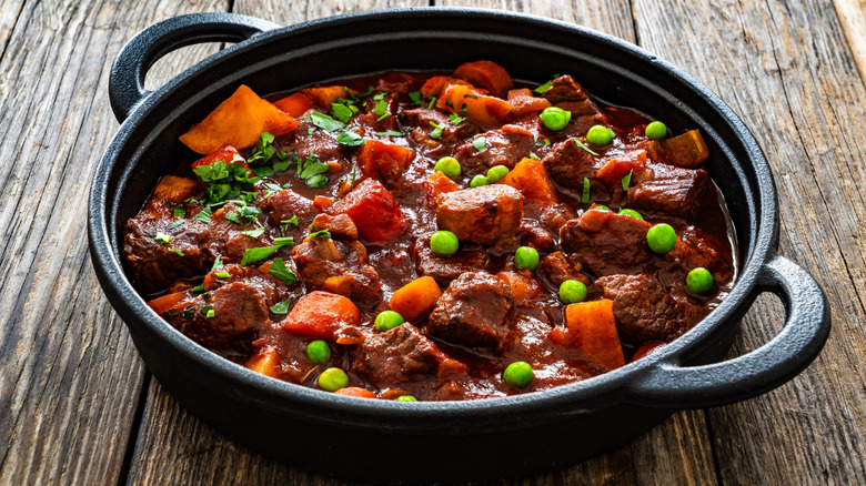 Beef stew in a cast iron pan on a wooden surface