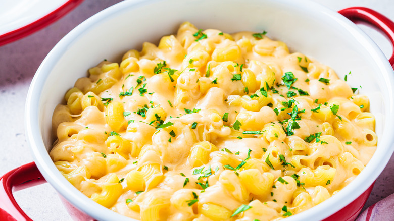 A pot of creamy mac and cheese with chopped parsley on top