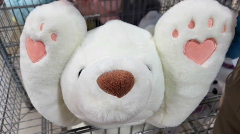 Close up of a white stuffed animal bear in a shopping cart