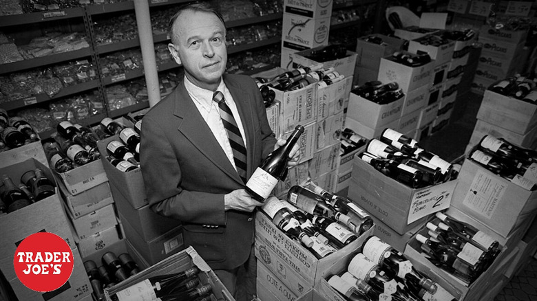 Joe Coulombe smiling at the camera surrounded by cases of wine