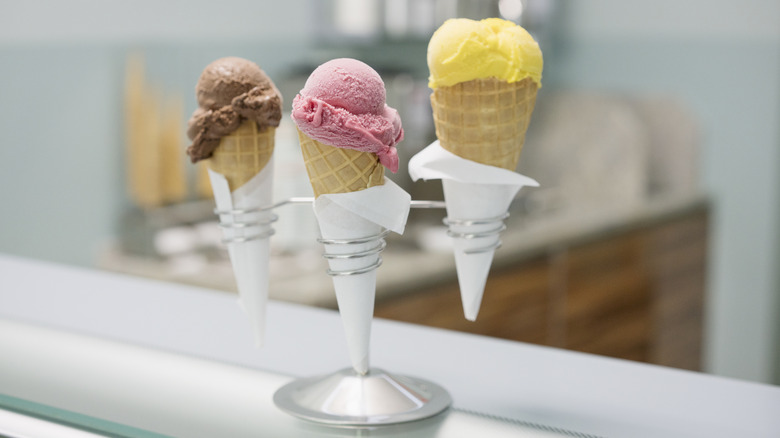 Close up of three ice cream cones on metal holders on a counter