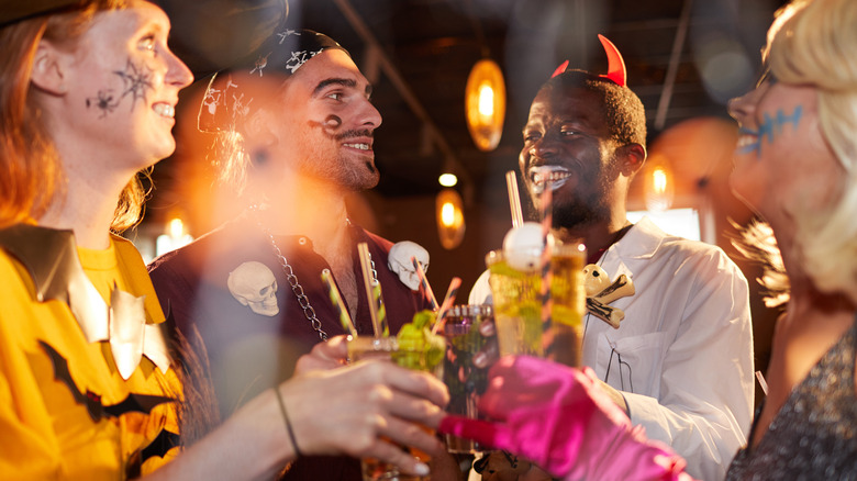 A group of people in Halloween costumes holding cocktails